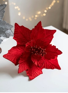Close-up of red artificial Christmas flower with glitter details on white surface