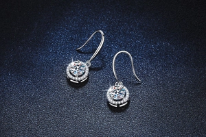 Macro detail of silver drop earrings featuring halo-set round moissanite with high fire