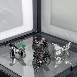 Set of four butterfly rings with black enamel, green glaze and pink stones in a box