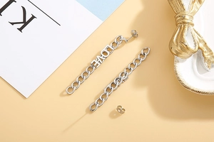 Close-up of silver long chain earrings with LOVE letters on a golden decorative tray