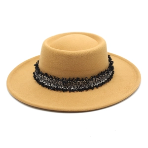 Detalle de sombrero boater de lana camel con banda tejida en blanco y negro con flecos