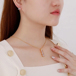 Dettaglio del set collana dorata e orecchini di zirconi indossati da una modella