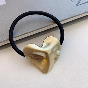 Minimalistische haarelastiek met een grove goudkleurige hartvormige metalen bedel