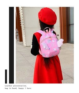 Pink toddler backpack with bunny print and polka dot wings shown in an outdoor setting