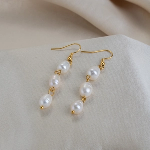 Detail view of triple freshwater pearl drop earrings in 18K gold plated stainless steel