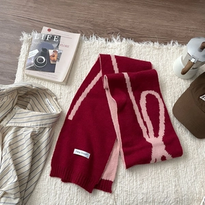 Detail of soft red and pink jacquard knit scarf with bow patterns in cozy winter setting