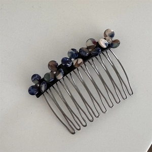 Detail view of 12-tooth metal hair comb with colorful resin flower decor on white background