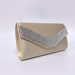 Detailed close-up of champagne satin clutch featuring elegant V-shaped rhinestone trim