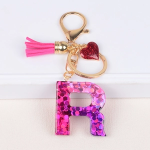 Detail of resin letter R keychain with pink sequins, magenta tassel and heart charm