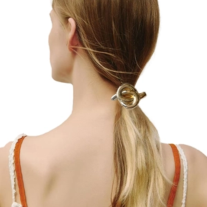 Detailed view of a knotted gold metal hair tie on a bun showing polished surface finish
