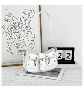 Detailed close-up of a white studded shoulder bag with silver hardware on a textured surface