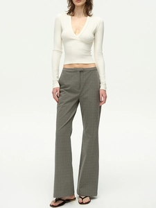 Dettaglio del crop top bianco con scollo a V e pantaloni a quadri grigi su modella
