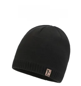 Close-up of black knit beanie featuring a brown leather logo and ribbed texture detail