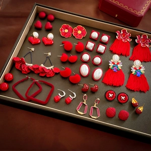 Flat lay of multiple red earrings featuring pearls, tassels, and heart shapes