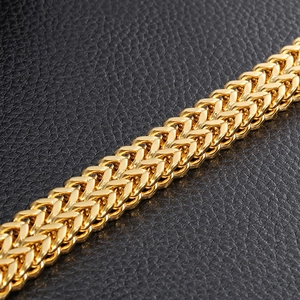 Macro shot of gold square fish scale chain on black leather background
