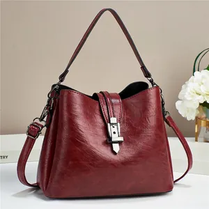 Close-up of a burgundy oil wax leather bucket bag with retro silver buckle and textures