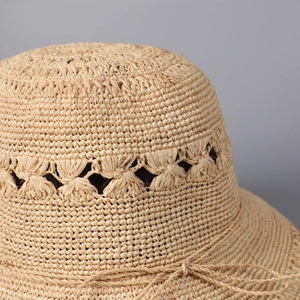 Gros plan d'un chapeau de paille en raphia fait main avec tissage ajouré et nœud délicat