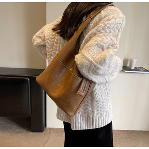Seitenansicht einer großen braunen Leder-Eimertasche, getragen von einem Modell für den Alltag