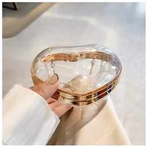 Detail of a transparent heart acrylic clutch with gold frame and chain strap