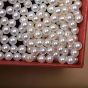 Macro shot of 4mm white freshwater pearls with pre-drilled holes in a red gift box