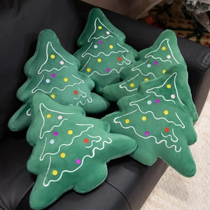 Soft green plush Christmas tree pillows with colorful dot embroidery on a leather sofa