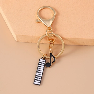 Golden musical keychain with piano keys and note charms on a creative display stand
