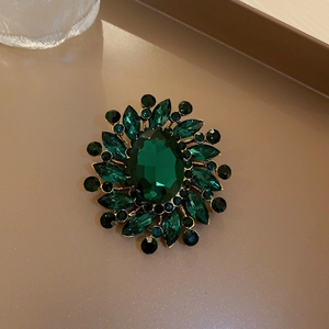 Macro shot of vintage emerald flower brooch with crystal petals and gold metal base