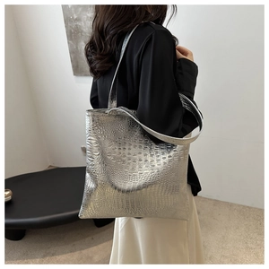 Macro shot of silver tote bag featuring crocodile embossed texture and metallic finish