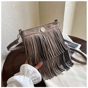 Detail of suede crossbody bag featuring elegant tassels and a secure magnetic snap closure