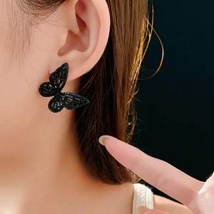 Close-up of black hollow butterfly stud earrings with rhinestones on a female model's ear