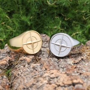 Detail of gold and silver nautical compass seal rings on rustic bark background