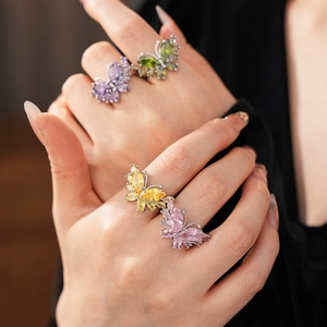 Détail de quatre bagues papillon avec zircons violets, verts, jaunes et roses colorés