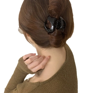 Minimalist black acrylic geometric hair claw clip shown on long brown hair from a side view