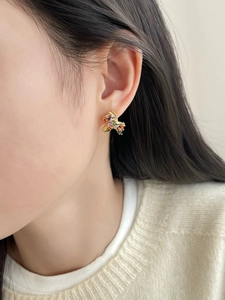 Close-up of a model wearing gold-plated pony stud earrings with colorful zircon stones