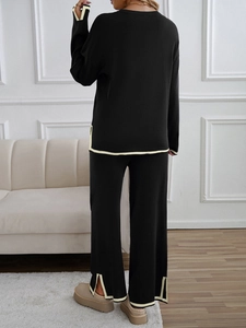 Detail of black knit set featuring beige contrast trim on sleeves and side slit pants