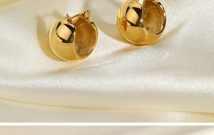 Macro view of 18K gold plated spherical earrings on soft white satin background