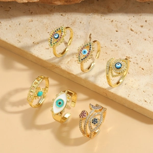 Detailed arrangement of gold evil eye rings with colorful zircon on a textured stone base