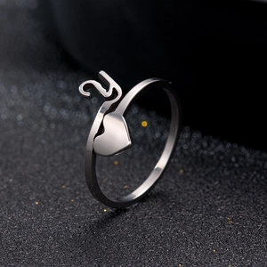 Macro side view of silver heart-shaped ring with S-letter detail on dark textured surface