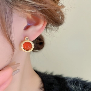 Gros plan d'une boucle d'oreille ronde vintage en or avec agate rouge et zircon sur modèle