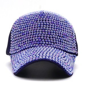 Dettaglio del cappellino blu scuro con perle iridescenti e riflessi metallici