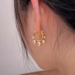 Close-up of elegant gold flower hoop earrings with five graduated champagne pearls