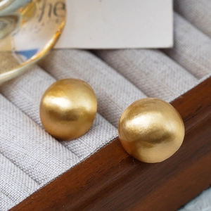 Matte gold oversized hemispherical stud earrings displayed in a luxury jewelry box