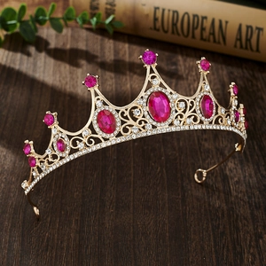Detail of golden princess crown with pink gemstones and rhinestones on wood