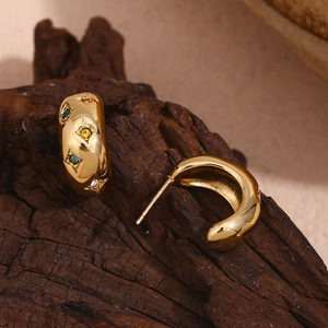 Macro shot of gold-plated hoop earrings featuring colorful zircon star-cut gemstones