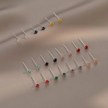 Macro detail of various colorful zircon stud earrings displayed on brown silk fabric
