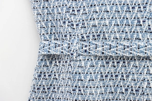 Detail of light blue tweed vest fabric texture with silver metallic thread and matching belt
