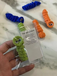 Detail of handmade crochet worry worms in colorful yarn with supportive poem cards