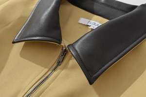 Detail of khaki jacket showing black leather collar, zipper and high-quality fabric texture