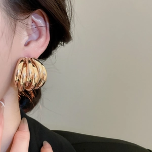 Close-up of stylish large multi-layer gold hoops earrings on model with sleek design