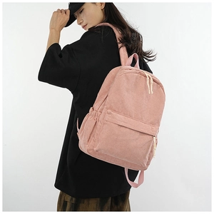 Detailed side view of pink corduroy backpack featuring white zipper pullers on model